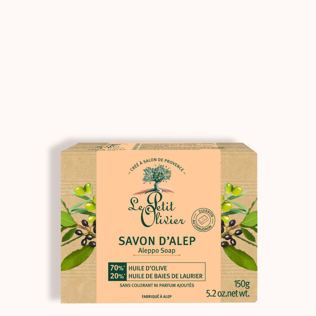 Une boîte de 150 g de savon d’Alep « Le Petit Olivier » se présente dans un emballage vert et jaune orné de branches d’olivier. Composé à 70 % d’huile d’olive et à 20 % d’huile de baies de laurier, il est idéal pour les peaux sensibles.