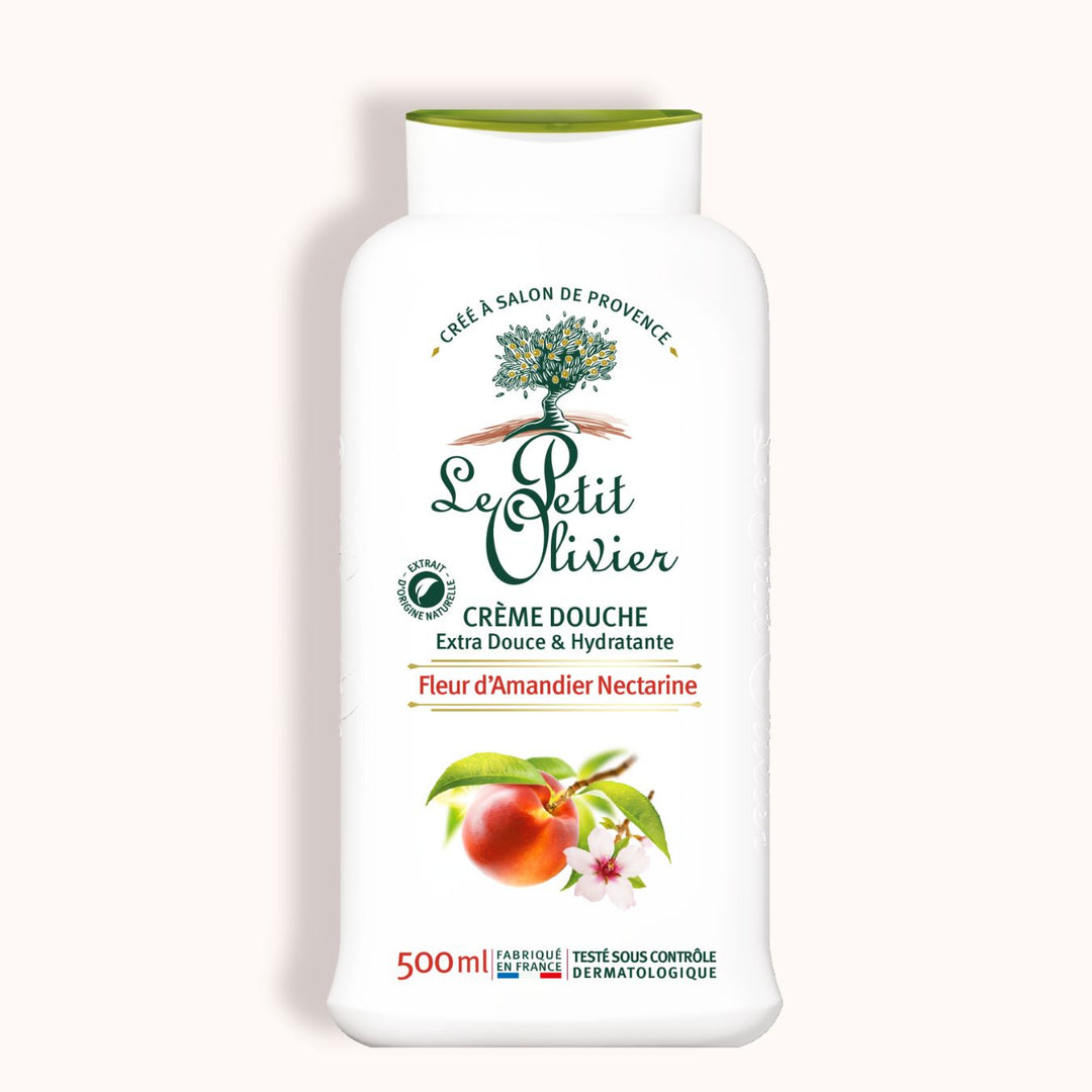 Un flacon blanc de « Le Petit Olivier Crème Douche Fleur d'Amandier Nectarine », orné de touches de vert et d'illustrations représentant des fleurs d'amandier et des nectarines. Points forts : « Extra Douce & Hydratante » pour une peau hydratée.