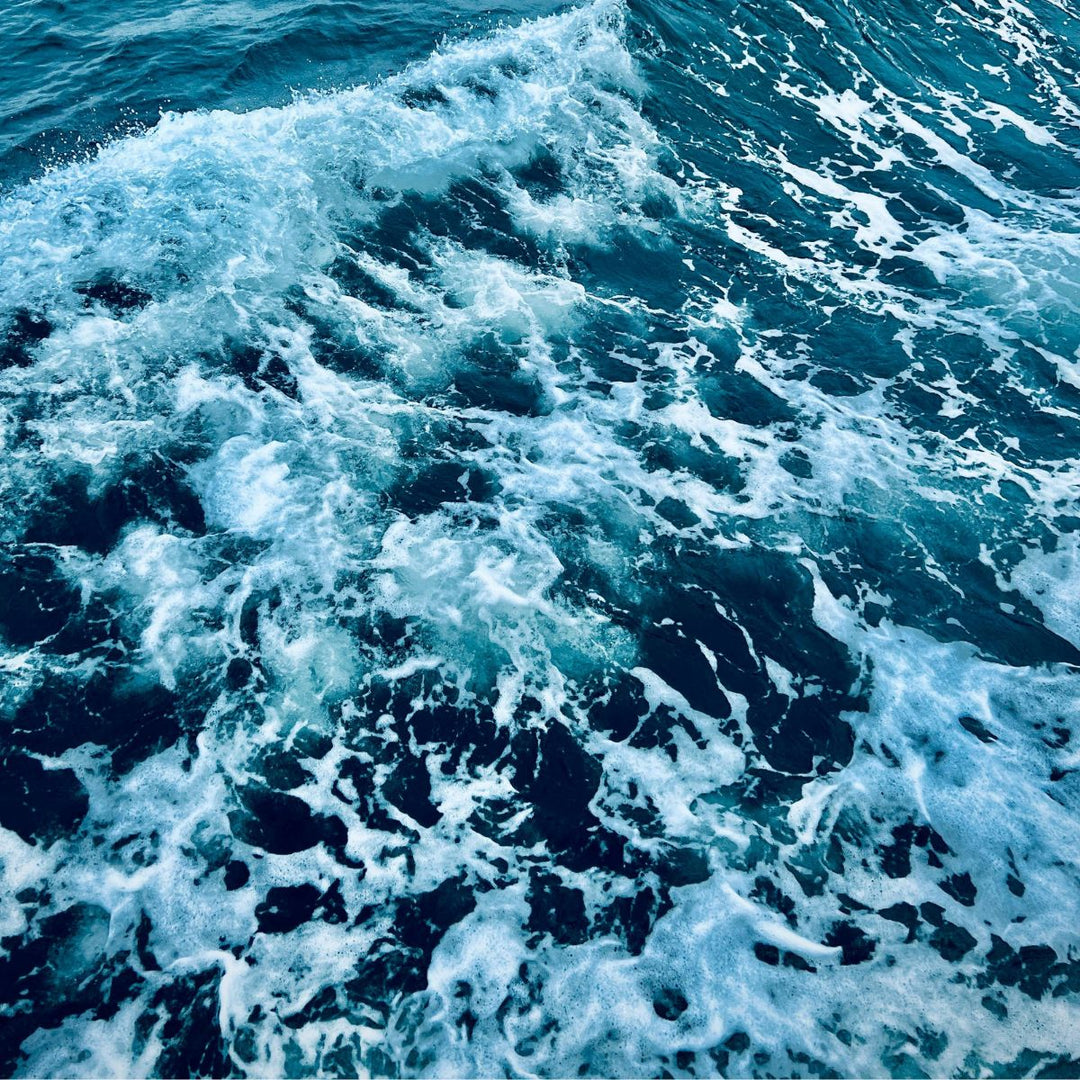 Un gros plan sur des vagues océaniques aux crêtes blanches et mousseuses se dressant sur une eau d'un bleu profond, évoquant la sensation rafraîchissante du Gel Douche Homme Vivifiant - Fraîcheur Marine de Le Petit Olivier et capturant le mouvement dynamique et la texture de la mer.