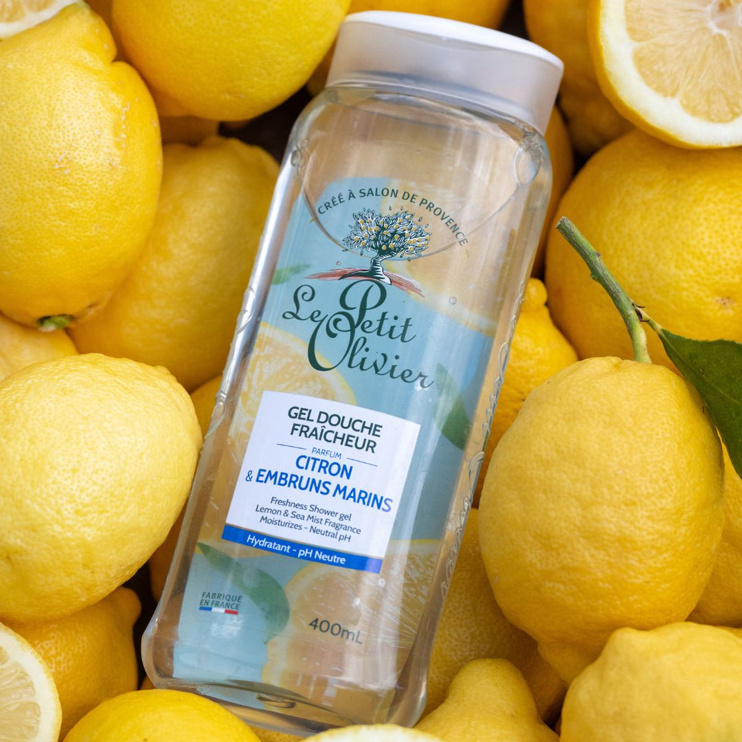 Une bouteille transparente de 400 ml de gel douche « Fraîcheur » de Le Petit Olivier trône au-dessus de citrons jaunes bien frais. L'étiquette, rédigée en français, porte la mention « fabriqué en France ».