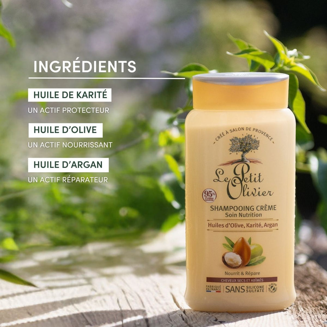 Un flacon de « Le Petit Olivier – Shampoing Cheveux Secs et Abîmés » repose sur une pierre au milieu de la verdure. Le texte en français met en avant son pouvoir nourrissant pour les cheveux secs, grâce à sa formule enrichie en huiles d'olive, de karité et d'argan, et sans sulfate.