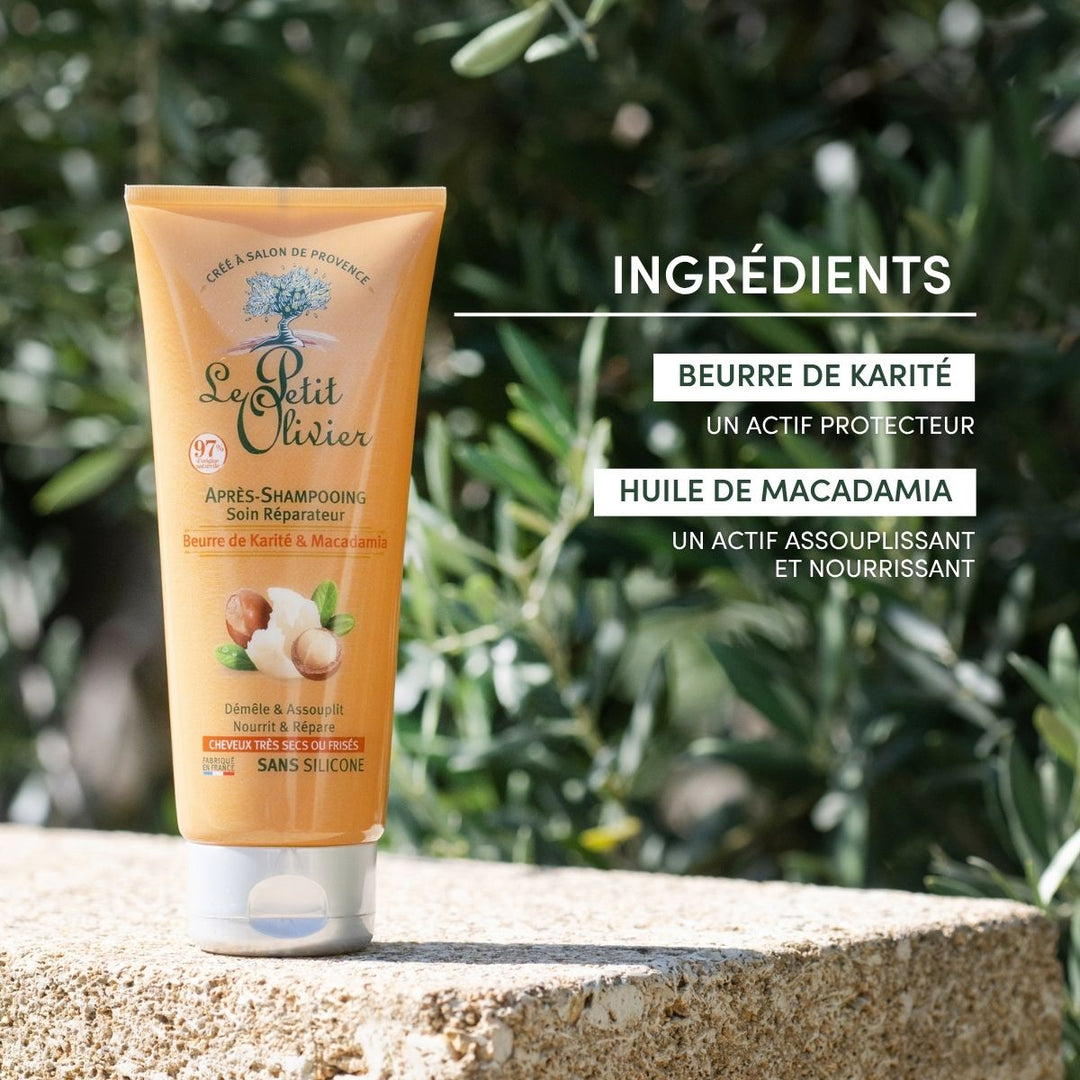 Un tube d’après-shampoing « Le Petit Olivier » pour cheveux très secs ou frisés repose sur une surface en pierre à l’extérieur, avec des feuilles vertes en arrière-plan. Sa formule sans silicone, enrichie en beurre de karité et en huile de macadamia, offre un soin réparateur pour les cheveux secs ou frisés.