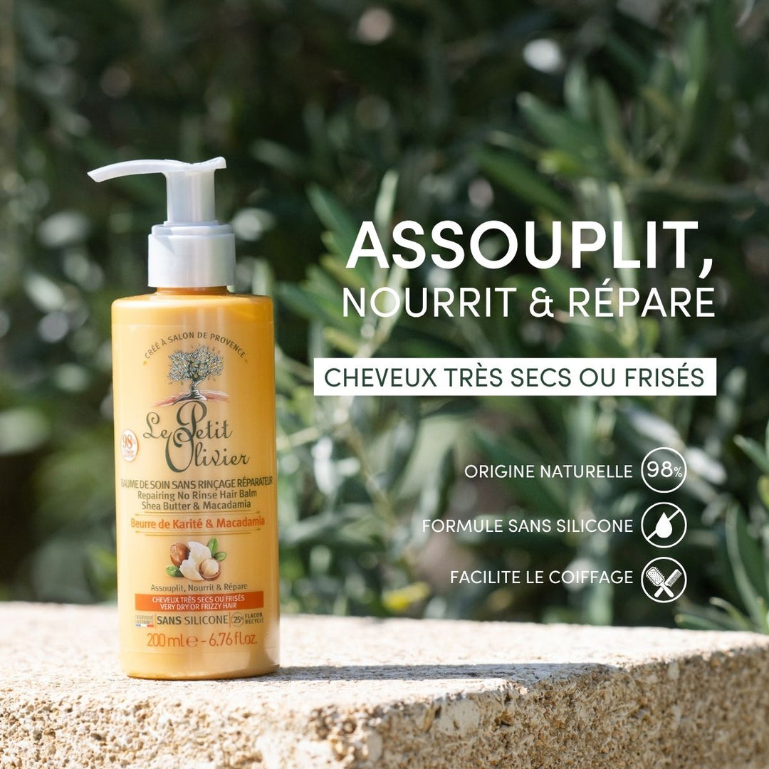 Un flacon de « Le Petit Olivier Baume de Soin Sans Rinçage Cheveux Très Secs ou Frisés » repose sur une pierre à l'extérieur, au milieu de la verdure. Le texte en français met en avant sa formule à base de beurre de karité pour cheveux très secs ou frisés — naturelle et sans silicone.