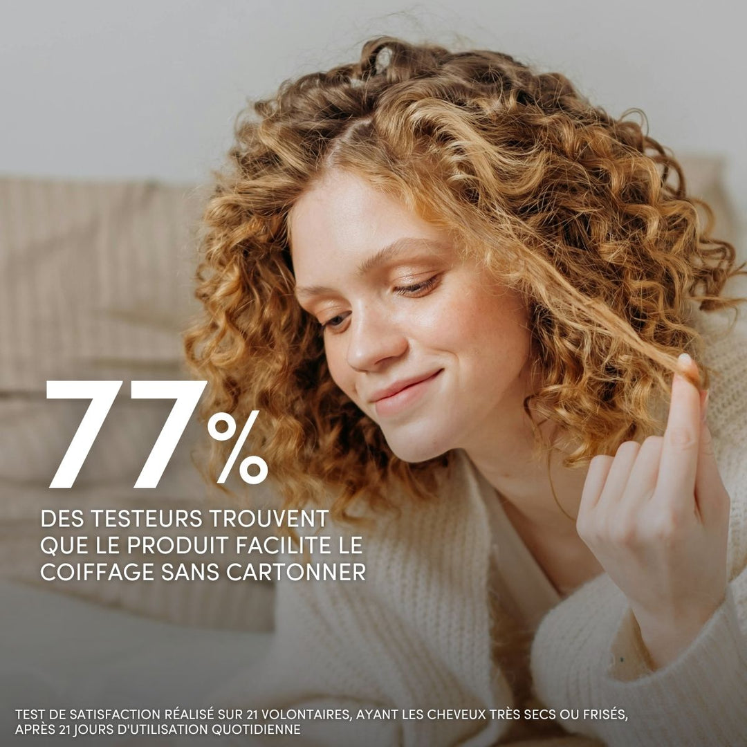 Une jeune femme aux cheveux blonds bouclés sourit et passe la main dans ses cheveux très secs. Texte : 77 % des personnes interrogées affirment que le Baume de Soin Sans Rinçage pour Cheveux Très Secs ou Frisés de Le Petit Olivier facilite le coiffage sans rendre les cheveux raides. Des informations complémentaires figurent en bas de page.