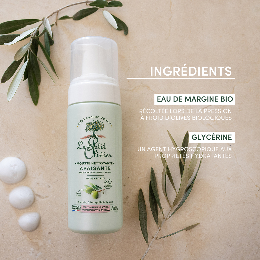 A bottle of Mousse Nettoyante Visage Apaisante rests on a beige surface with olive branches and olives. Text highlights organic olive water, extrait d’olive, and glycerin—ideal for dry skin, with properties listed in French.