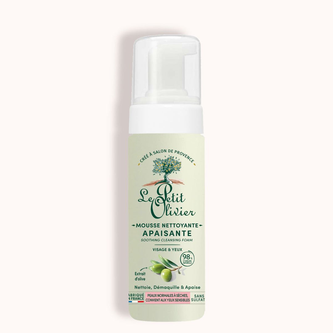 A bottle of Mousse Nettoyante Visage Apaisante with olive extract, white pump, green label, and French text—ideal for face and eyes, suitable for normal to sensitive or dry skin.