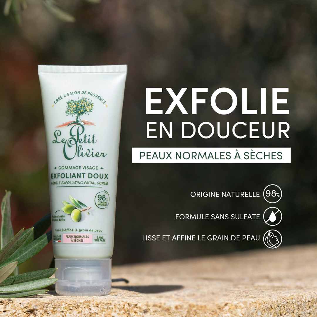 Un tube de « Le Petit Olivier Gommage Visage Exfoliant Doux » est posé à l'extérieur sur une pierre, au milieu de la verdure. Son étiquette met en avant sa formule d'origine naturelle, sans sulfate, et à base de poudre de noyau d'olive, pour une exfoliation en douceur des peaux normales à sèches.