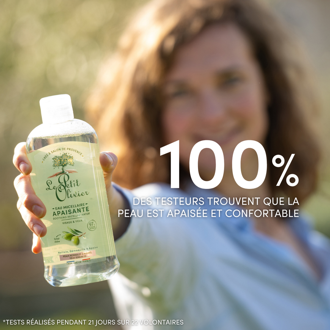 Une personne tient devant la caméra un flacon d’Eau Micellaire Démaquillante Visage & Yeux Sensibles « Le Petit Olivier ». Le texte indique : « 100 % des testeurs trouvent la peau apaisée et confortable. À l’extrait d’olive, idéale pour les peaux sensibles. ».