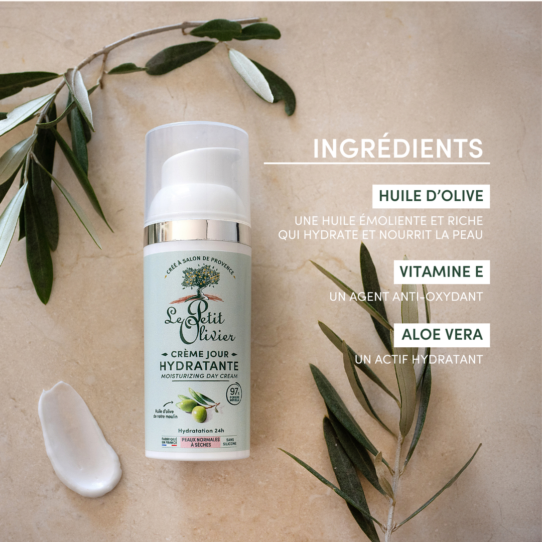 Un flacon de « Le Petit Olivier Crème Hydratante Visage Peaux Normales à Sèches » repose sur un fond beige orné de feuilles d’olivier et de crème, mettant en avant l’huile d’olive, la vitamine E et l’aloe vera pour hydrater la peau ; ce produit convient aux peaux sèches à normales.