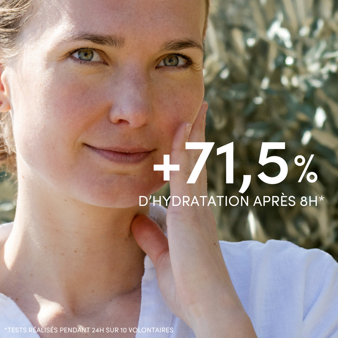 Une femme au teint clair sourit doucement en plein air, entourée de verdure. Le texte indique : +71,5 % d’hydratation après 8 h* avec la Crème Hydratante Visage Peaux Normales à Sèches de Le Petit Olivier. Idéale pour les peaux sèches ou en complément d’une crème hydratante à l’huile d’olive.