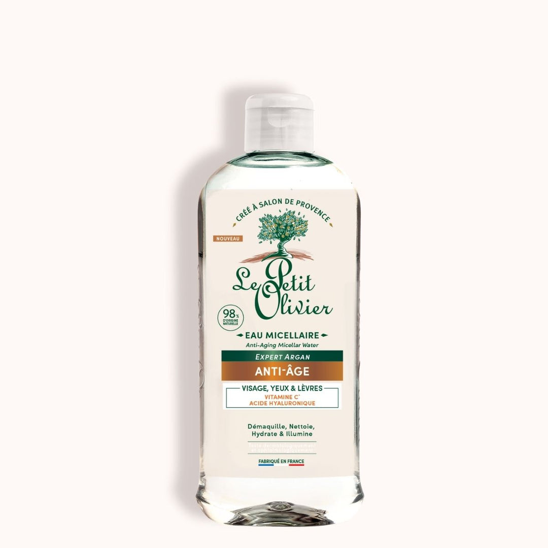 Un flacon transparent d'Eau Micellaire Anti-Âge « Le Petit Olivier », orné d'une étiquette verte et blanche sur laquelle figure un logo représentant un arbre, mettant en avant l'extrait d'argan et l'acide hyaluronique, et adapté au visage, aux yeux et aux lèvres.