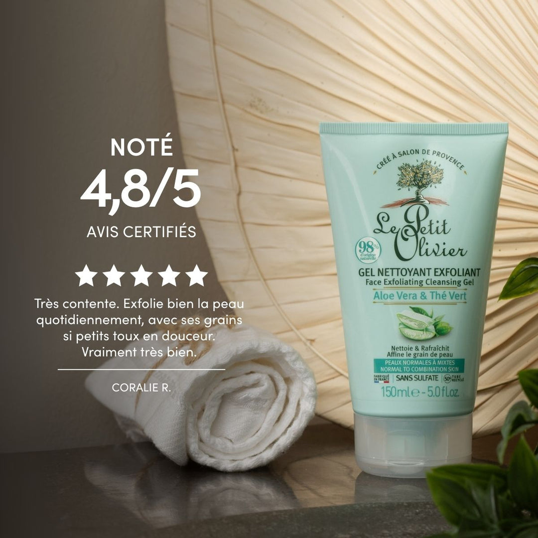 Un tube de gel nettoyant exfoliant « Le Petit Olivier » est posé à la verticale à côté d'une serviette blanche enroulée sur une surface sombre, le tout sur fond beige, accompagné d'un avis client français noté cinq étoiles qui vante ses exfoliants naturels.