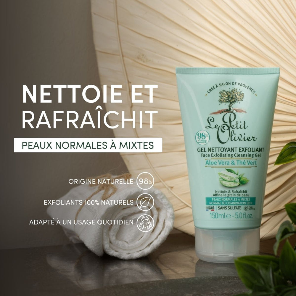 Un tube de gel nettoyant exfoliant « Le Petit Olivier » est posé à côté d'une serviette blanche enroulée et d'une fleur blanche. Une étiquette indique qu'il contient des exfoliants naturels, de l'aloe vera, des ingrédients d'origine naturelle, qu'il convient à un usage quotidien et qu'il est destiné aux peaux normales à mixtes.