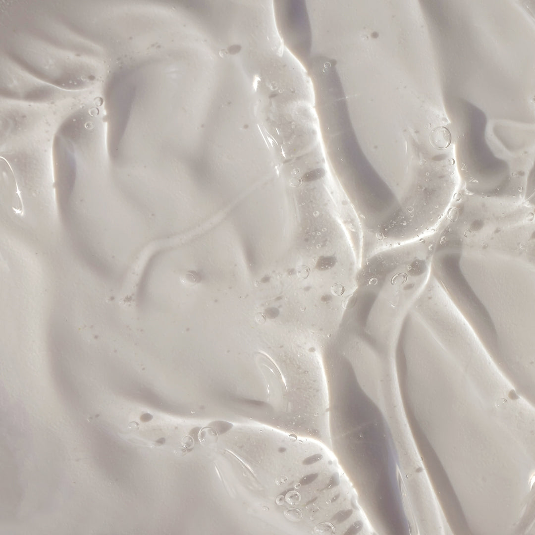 Un gros plan sur le « Recharge Pur Savon Liquide - Sans Parfum » de Le Petit Olivier révèle sa texture onctueuse, d'un blanc laiteux, parsemée de légères ondulations, de bulles et de reflets qui mettent en valeur sa surface brillante et sa base végétale pure.