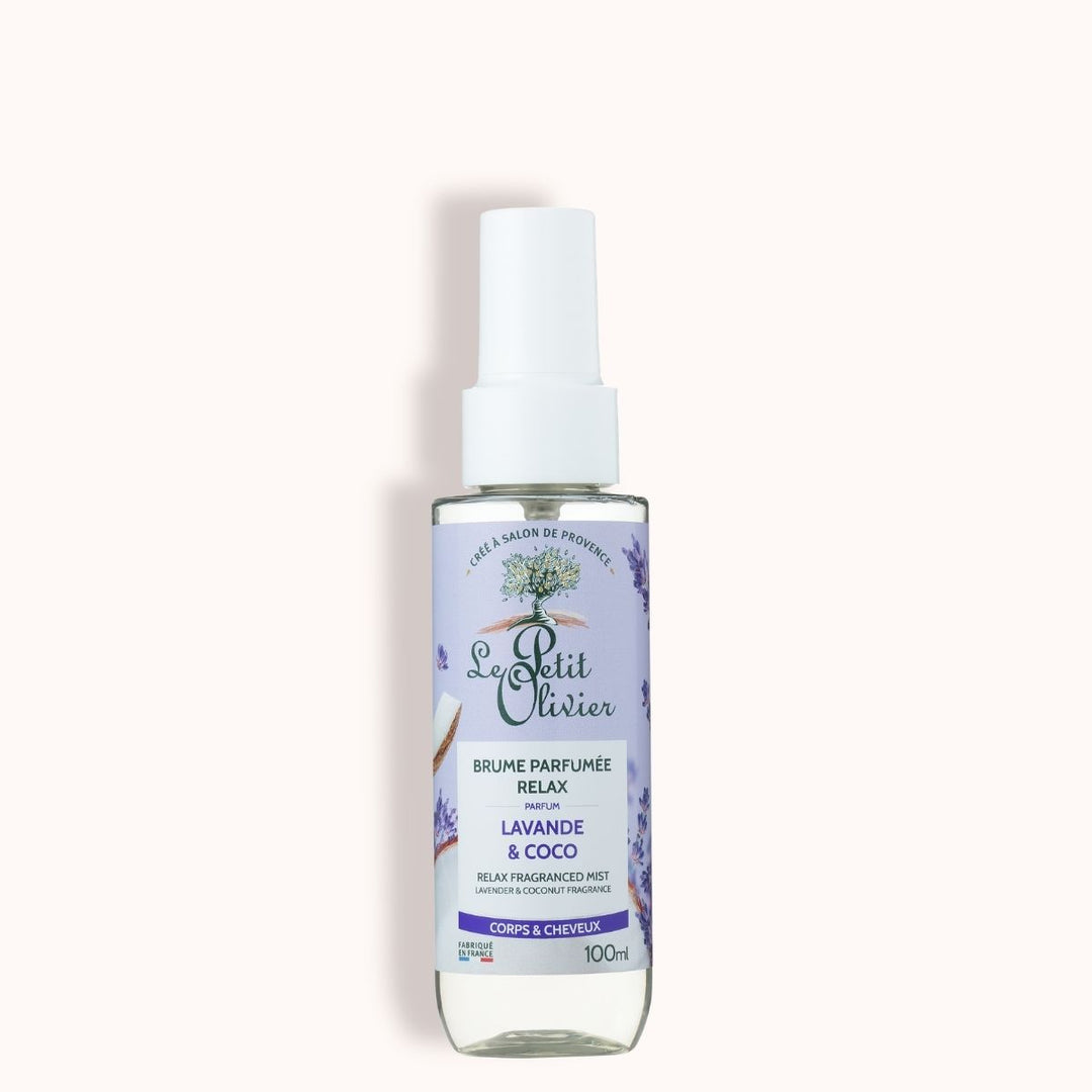 Un flacon vaporisateur transparent de 100 ml de « Le Petit Olivier Brume Parfumée Relax » pour le corps et les cheveux, au parfum de lavande et de noix de coco, orné d'une étiquette violette avec des illustrations de lavande et d'un bouchon blanc.