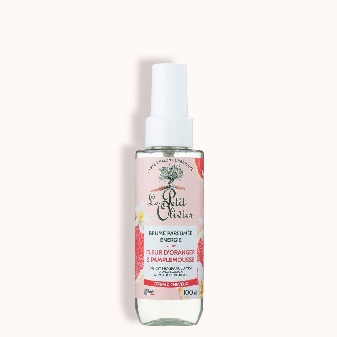 Un flacon de 100 ml de « Le Petit Olivier Brume Parfumée Énergie », avec une étiquette rose illustrée d’agrumes et un vaporisateur blanc. Idéal pour rafraîchir le corps et les cheveux. Parfumé à la fleur d’oranger et au pamplemousse.