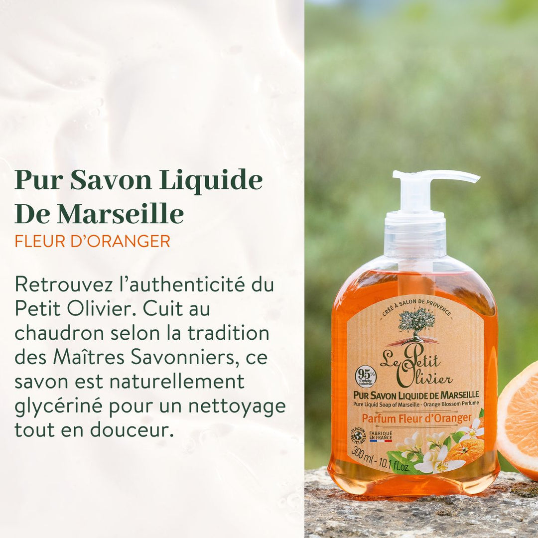 Un flacon du coffret « Découverte » de Le Petit Olivier – « Purs Savons Liquides de Marseille », contenant un savon aux reflets orangés et muni d’une pompe, repose sur une pierre à côté d’une tranche d’orange. Le texte met en avant sa fabrication marseillaise traditionnelle, douce et authentique.