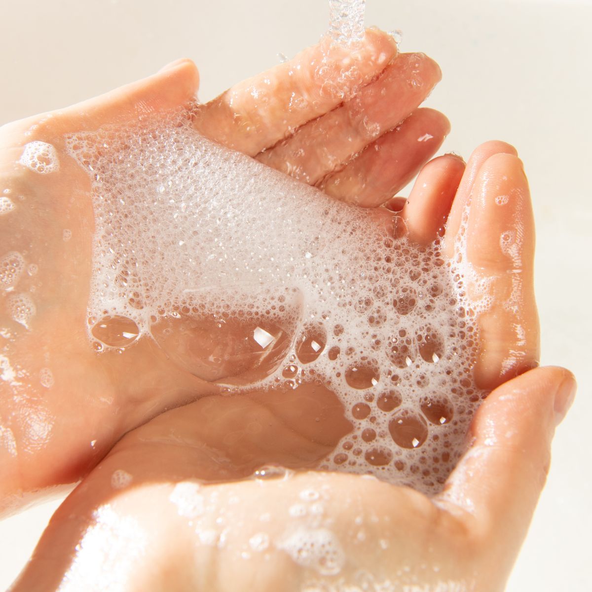 Gros plan sur des mains que l'on se lave à l'eau et à la mousse du « Pack Découverte - Savonnettes Extra Douces » de Le Petit Olivier, fabriqué en France, mettant en avant une bonne hygiène des mains.