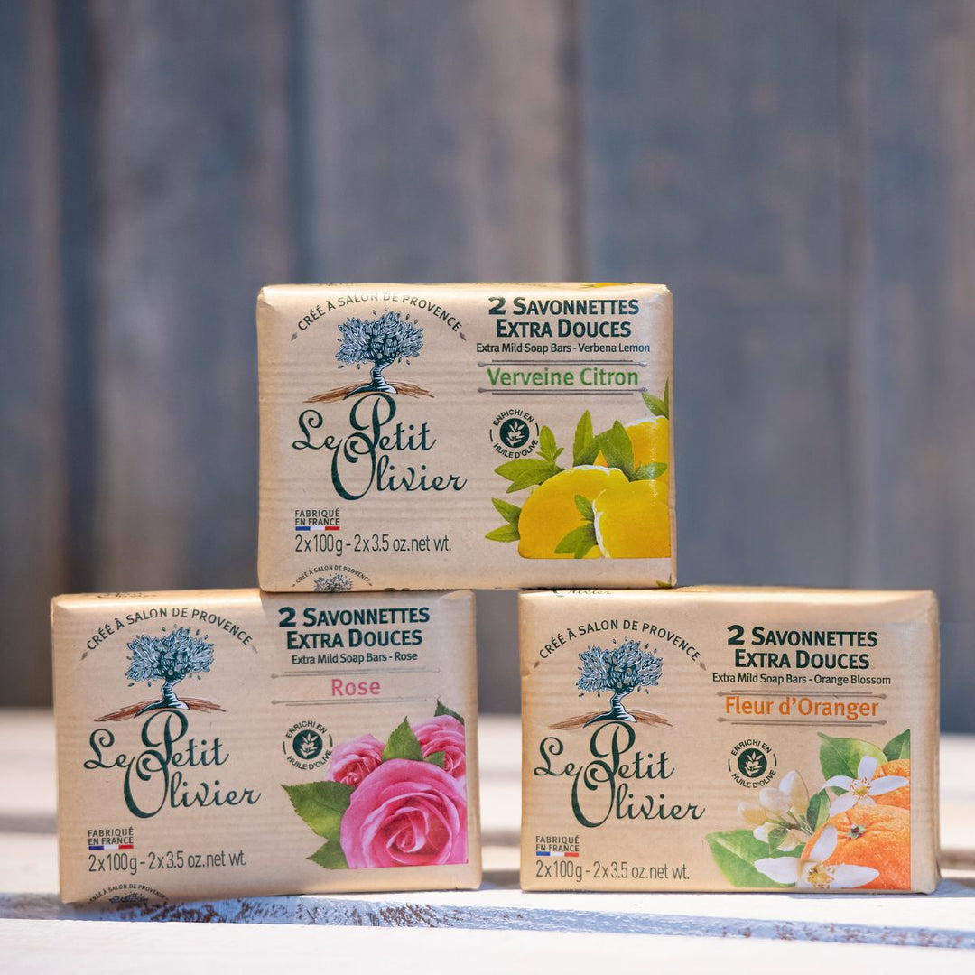 Trois savonnettes « Le Petit Olivier » Extra Douces issues du coffret Découverte sont empilées à l'extérieur. Parfums : verveine-citron, rose, fleur d'oranger. Chaque savonnette, fabriquée en France, est emballée dans du papier naturel orné de motifs floraux.