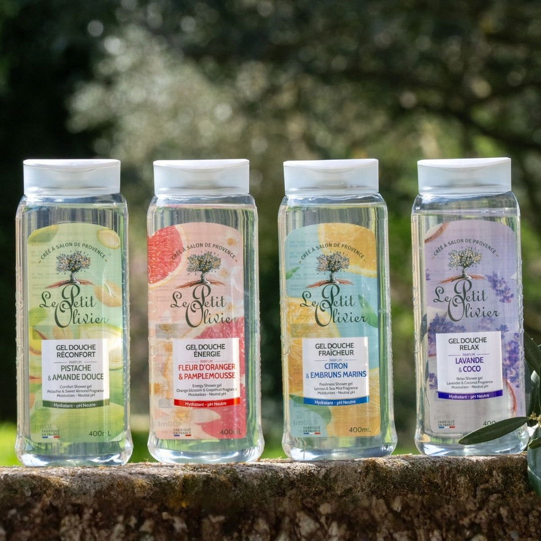 Le Pack Découverte de Le Petit Olivier - Gels Douche 400 ml propose quatre gels douche hydratants au pH neutre, aux parfums de pistache et d'amande douce, de fleur d'oranger et de pamplemousse, de citron et d'embruns, ainsi que de lavande et de noix de coco, présentés en extérieur au milieu d'une végétation luxuriante.
