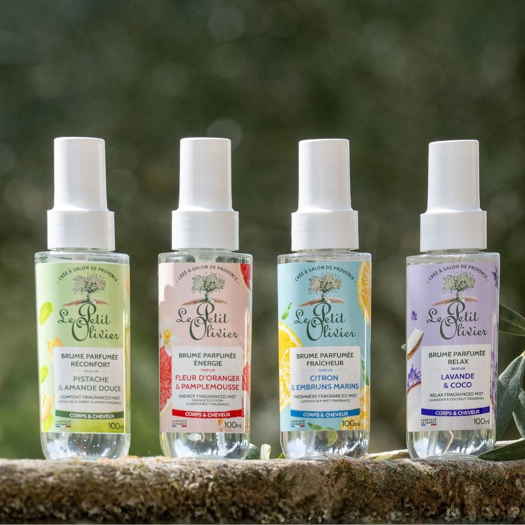 Quatre flacons du coffret « Découverte » de Le Petit Olivier – Brumes Parfumées sont présentés en extérieur, avec les parfums suivants : Pistache & Amande douce, Fleur d'oranger & Pamplemousse, Citron & Brise marine, et Lavande & Noix de coco. Fabriqué en France.