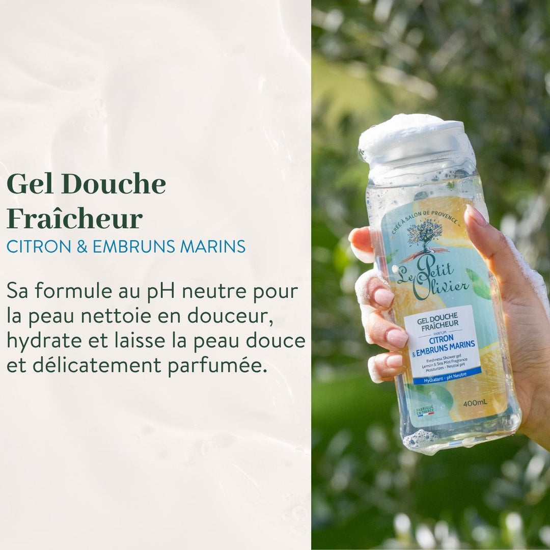 Une main tient un flacon transparent de « Le Petit Olivier Duo Fraîcheur - Gel Douche et Brume Parfumée », surmonté de bulles mousseuses. Sur fond de verdure rafraîchissante, un texte en français met en avant sa « douceur et fraîcheur ».
