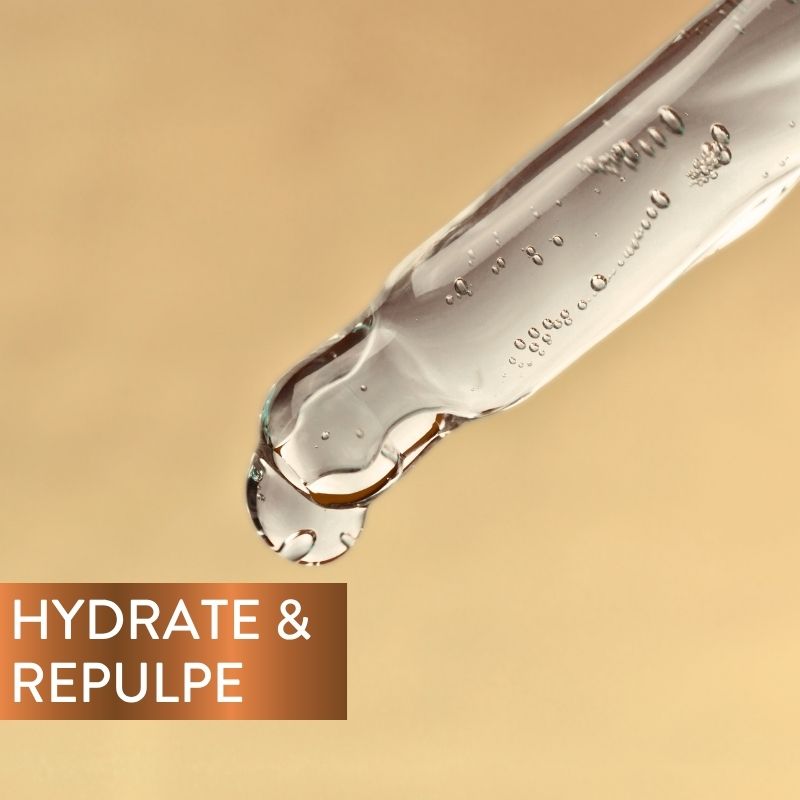 Gros plan sur un compte-gouttes déversant un liquide transparent sur un fond beige. Dans un coin, on peut lire « HYDRATE & REPULPE » en lettres blanches sur un fond marron dégradé.