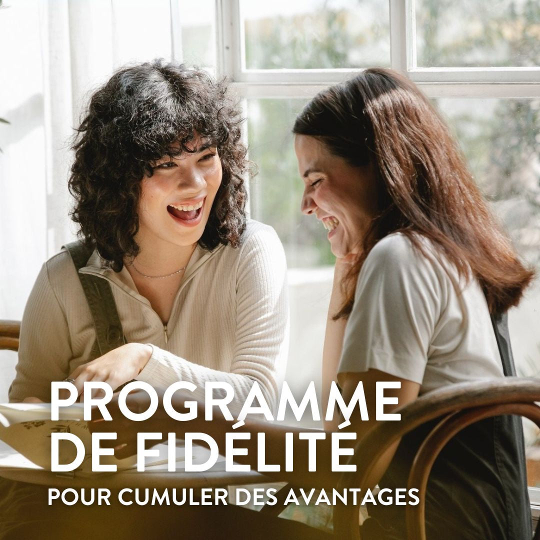 Deux femmes sont assises près d'une fenêtre, souriantes et en train de discuter. Le texte en français indique : « Programme de fidélité pour cumuler des avantages », faisant la promotion d'un programme de fidélité.