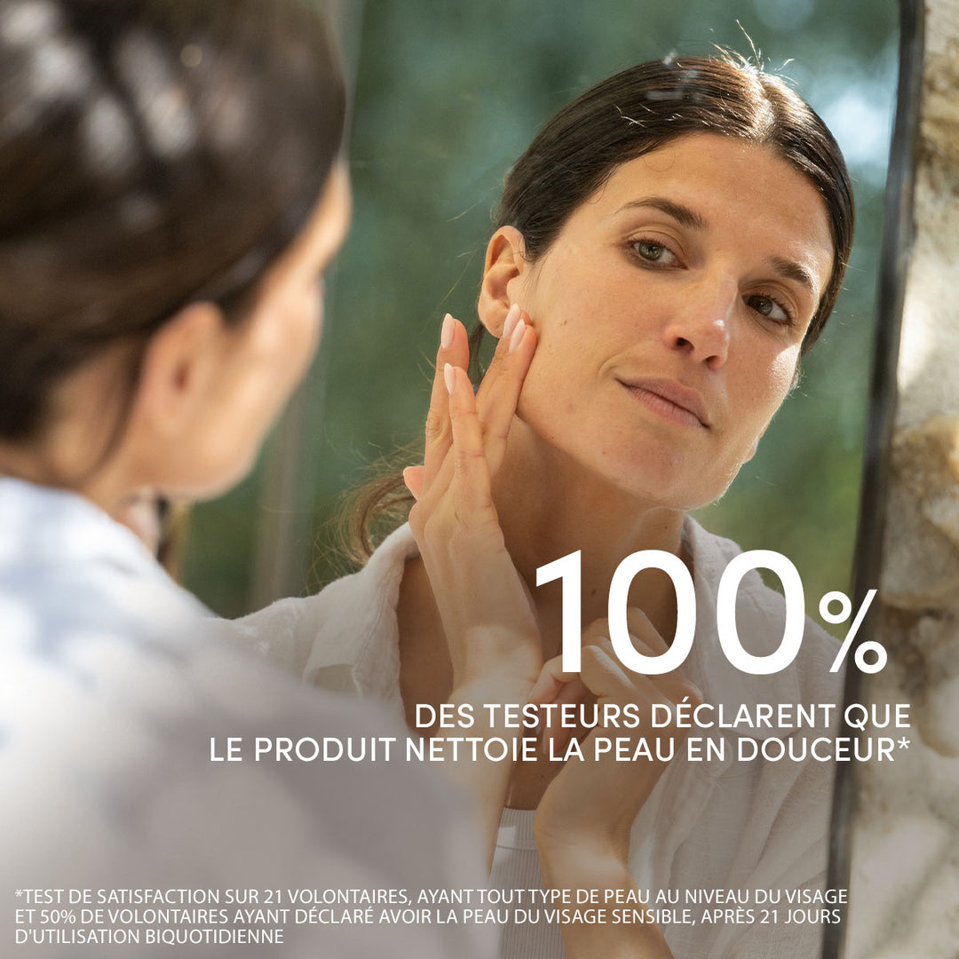 Une femme se caresse délicatement le visage devant le miroir de la salle de bains. Le texte indique : « 100 % des testeurs déclarent que le Gel Nettoyant Visage Douceur de Le Petit Olivier nettoie la peau en douceur. » Mentions légales en bas de page.