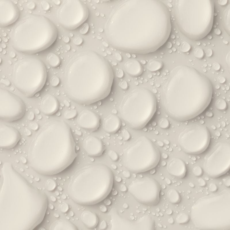 Des gouttelettes d'eau, grandes et petites, étaient dispersées sur une surface lisse de couleur crème, formant un motif composé de gouttes de tailles et de formes variées.
